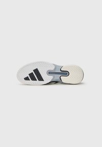 Semelle de chaussure de sport en noir et blanc avec un motif en caoutchouc texturé, comportant un logo à trois bandes bien en vue et un design de semelle en chevron.