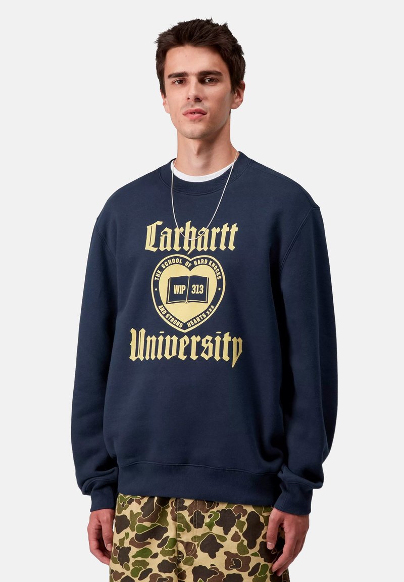 Sudadera azul marino de algodón, con un gran texto gráfico en dorado que dice "Carhartt University" y un emblema en la parte delantera.