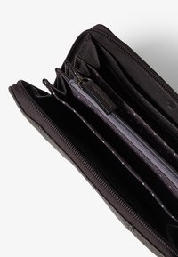 Schwarze Lederbörse mit mehreren Fächern, glatter Textur, Reißverschluss und grauem Innenraum mit einem Punktenmuster.