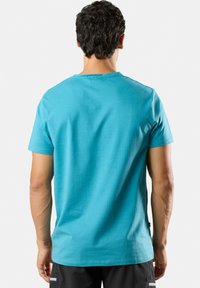 Türkises T-Shirt mit kurzen Ärmeln aus Baumwolle, mit Rundhalsausschnitt und glatter Textur, von hinten auf einem neutralen Hintergrund gezeigt.