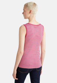 Canotta a righe rosa e bianche con scollatura tonda, design senza maniche e forma attillata, abbinata a jeans scuri.