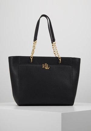 Borsa tote in pelle nera con manici a catena dorata e logo "RLL" dorato sul davanti, esposta su un piedistallo bianco contro uno sfondo grigio.