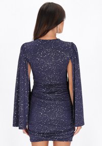 Marineblaues Kleid mit Glitzerakzenten, taillierte Silhouette, lange kapuzenartige Ärmel, Ausschnitte hinten und Raffung im Rock.