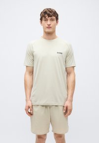 Ελαφρώς μπεζ αθλητική μπλούζα με κοντά μανίκια και στρογγυλή λαιμόκοψη, με μικρό μαύρο λογότυπο "BOSS" στο στήθος, σετ με ταιριαστό σορτς.