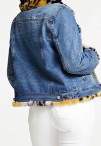 Chaqueta de mezclilla con ribete de pelaje sintético, con un cuerpo azul y pelaje multicolor alrededor del dobladillo. Incluye detalles de botones y un corte clásico.