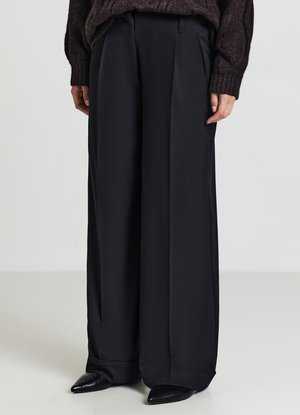 Schwarze weit geschnittene Hose aus glattem Stoff mit vorderen Falten, die eine taillierte Passform und eine weiche, fließende Textur aufweist.