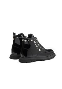 Stivaletti neri lucidi con suola chunky e borchie a forma di cuore argentate lungo l'area dei lacci, visti da dietro e di lato.