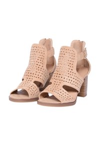 Sandali in suede perforato beige con tacco, con punta aperta, cinturini alla caviglia regolabili e tacco quadrato testurizzato. Presentano ritagli geometrici.