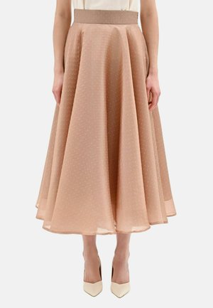 Gonna midi beige con piccoli pois bianchi, design svasato, vita alta, indossata con tacchi bianchi a punta e una maglia infilata.