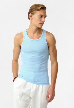 Lichtblauw geribd tanktop met een aansluitende pasvorm, ronde halslijn en brede schouderbanden, gecombineerd met witte geplooide broeken.