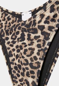 Dół bikini w panterkę z czarną lamówką i widoczną białą wszywaną metką na pasku.