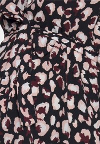 Černá tkanina s růžovým a burgundským leopardím vzorem. Obsahuje detail s uvázaným pasem a jemný, texturovaný materiál.