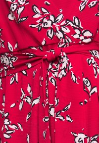 Tela roja con un acabado texturizado, con un patrón floral en blanco y negro. El detalle de la cintura atada realza el diseño.