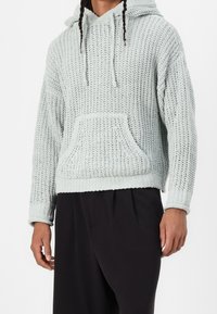 Sudadera de punto azul claro con una superficie texturizada, cordones, bolsillo frontal y puños acanalados. Corte casual con una silueta relajada.