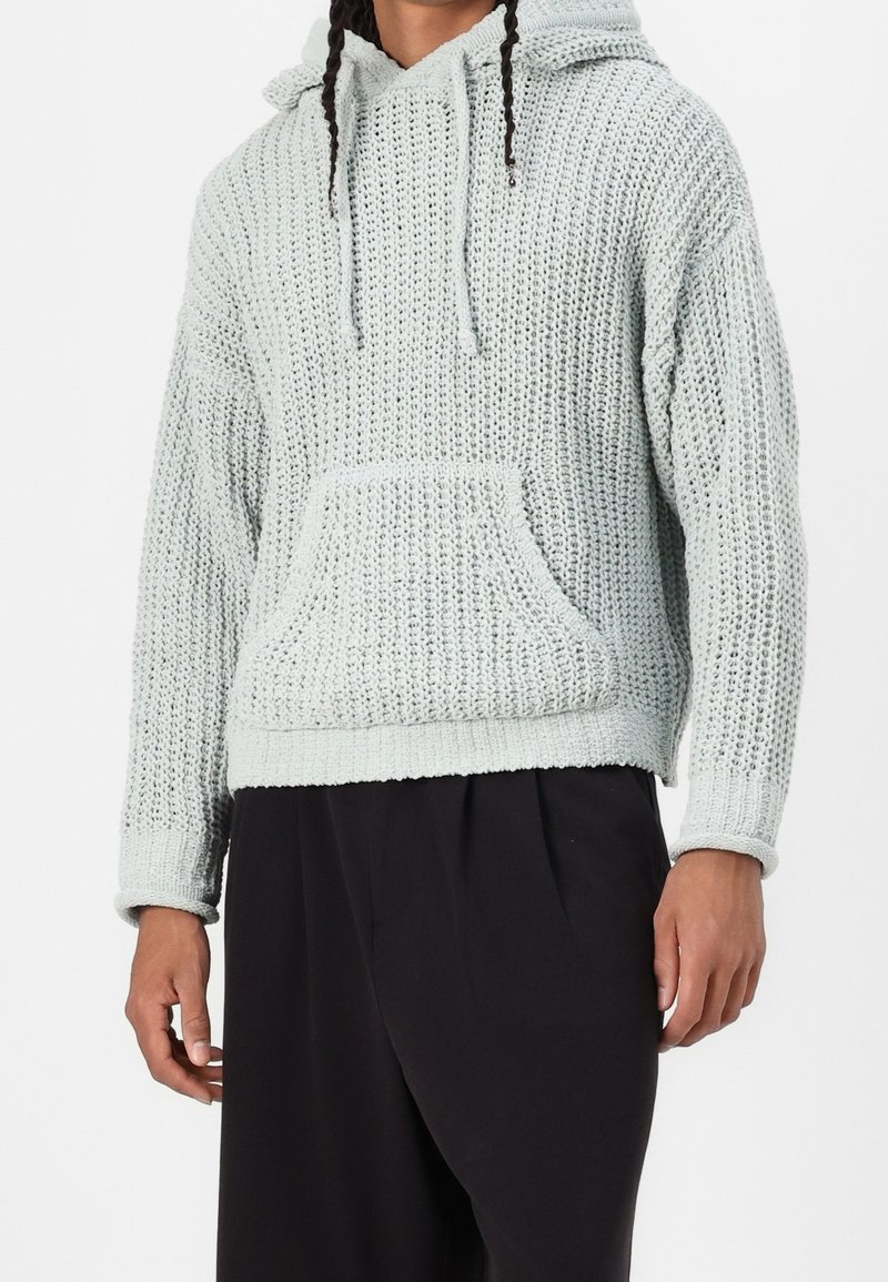 Sudadera de punto azul claro con una superficie texturizada, cordones, bolsillo frontal y puños acanalados. Corte casual con una silueta relajada.