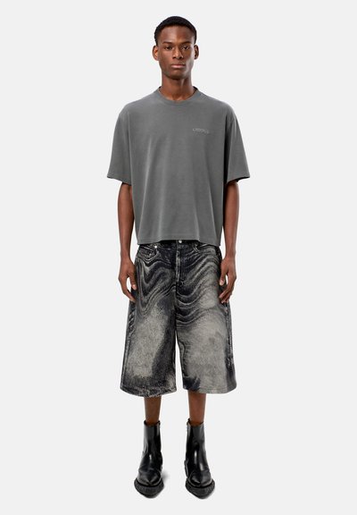 Gray cotton oversized t-shirt with a crew neck, paired with wide black denim shorts featuring a marbled pattern and black ankle boots.