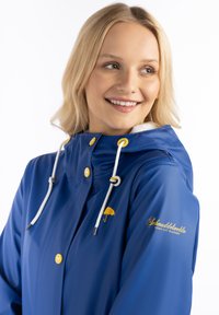 Blauer wasserdichter Regenmantel mit weißen Kordeln, gelben Akzenten und einem Regenschirm-Logo. Verfügt über einen hohen Kragen und Druckknopfverschlüsse vorne.