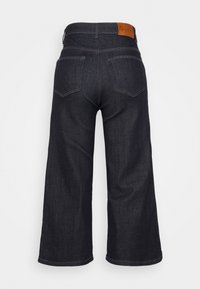 Tmavě modré džíny s širokými nohavicemi a vysokým pasem, s dvěma zadními kapsami a hnědým koženým štítkem značky vzadu. Hladká textura.