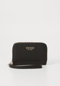 Juodas piniginė su tekstūruota paviršiumi, su aukso "GUESS EST 1981" logotipu, užtrauktuku uždarymo ir rankine. Stačiakampio formos.