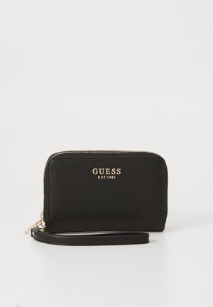 Black wallet with a textured surface, featuring a gold "GUESS EST 1981" logo, zip closure, and wrist strap. Rectangular shape.