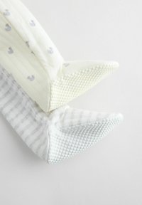 Kaks tekstuuriga beebipaput: üks helekollane, reljeefse pardimustriga, teine halli triibulise kangaga ning täpilise tallaga haarduvuse tagamiseks.