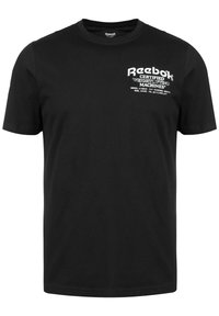 Černé bavlněné tričko s bílým textem na levé hrudi. Text zahrnuje název značky a "Certifikované vzpěračské stroje."