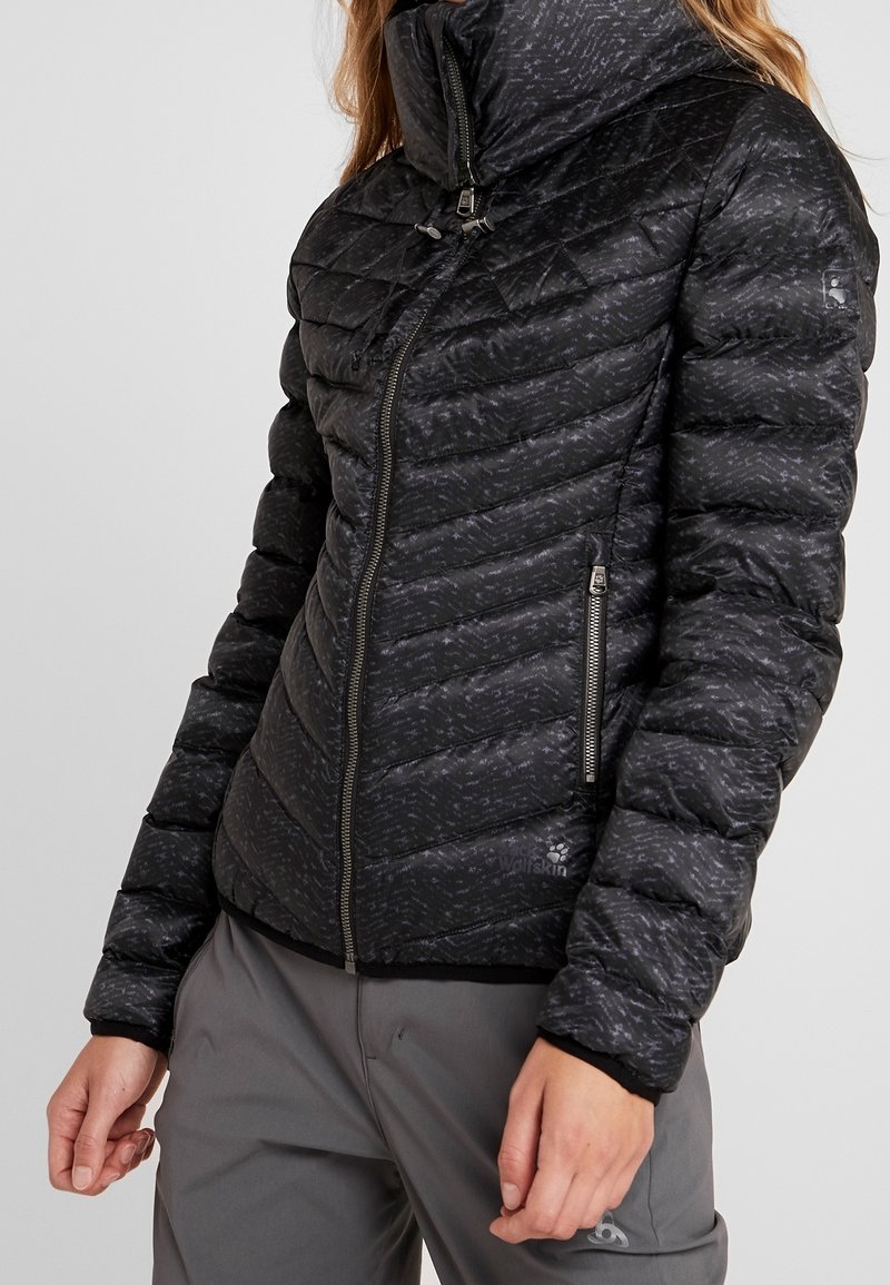 Vadderad svart kviltad jacka med hög krage, texturerad yta, sidofickor med dragkedja och logotyp på nederkanten. Slät tygfinish.