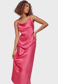 Satin pink slip dress with thin straps, featuring a relaxed fit and subtle draping detail. Smooth, glossy texture enhances elegance.