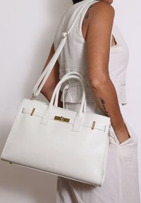 Borsa a mano in pelle bianca con manici superiori e tracolla rimovibile. Presenta hardware dorato, finitura testurizzata e una chiusura sicura con gancio.