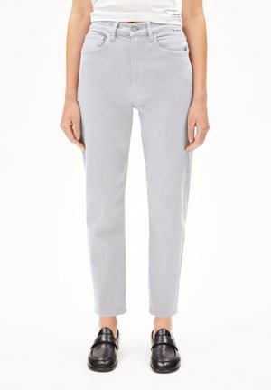 Jasnoszare jeansy z wysokim stanem i prostymi nogawkami, noszone z czarnymi mokasynami, pokazane od talii do stóp na jednolitym białym tle.