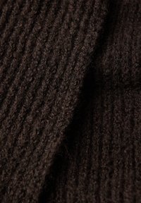 Tissu tricoté marron foncé avec une texture côtelée. Le matériau semble doux et pelucheux, mettant en valeur une épaisseur variable des fils.