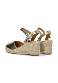 Sandalias de cuña metálica dorada con punta cerrada, correa para el tobillo y plataforma de yute trenzado. Presenta detalles texturizados en la cuña.