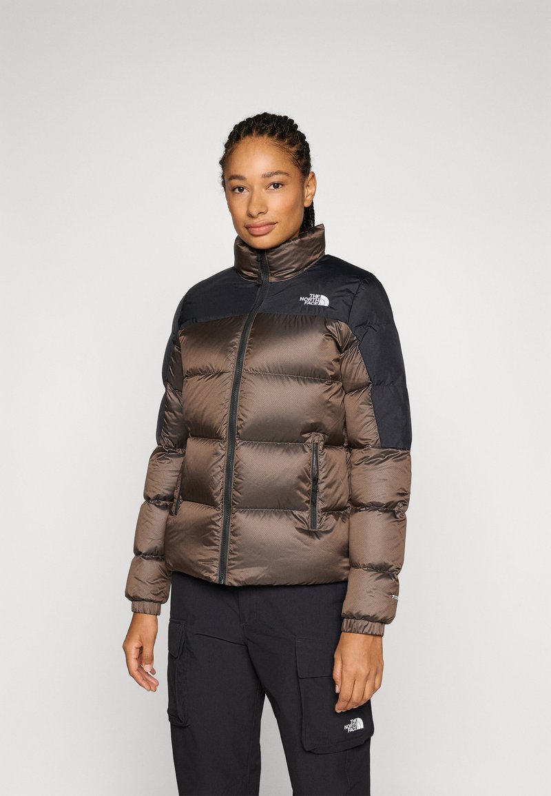 Pufferjack in bruin nylon met zwarte schouderaccenten. Bevat een hoge kraag, ritssluiting en zijzakken voor opbergruimte.