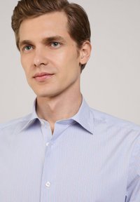 Jasnoniebieska koszula z guzikami w paski z klasycznym kołnierzykiem, z cienkimi pionowymi paskami w kolorze różowym oraz subtelnym połyskiem tkaniny.