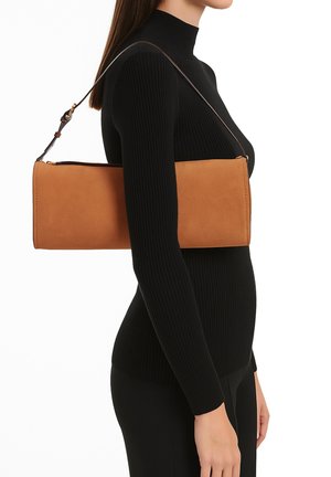 Borsa a spalla in suede marrone con forma rettangolare, dotata di una cerniera dorata e di una tracolla in pelle, indossata di lato su un outfit nero.