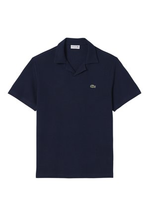 Polo de manga corta azul marino con cuello abierto y pequeño logo de cocodrilo verde en el pecho izquierdo.