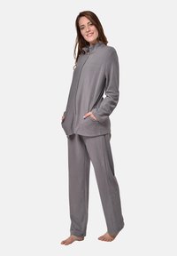 Grauem Fleece-Loungewear-Set mit Reißverschlussjacke und Taschen sowie passenden Hosen. Weicher Textur, lässige Passform und lange Ärmel.