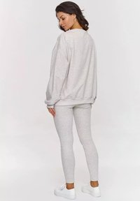 Szary, oversize'owy sweatshirt i dopasowane legginsy. Miękka tkanina o elastycznej strukturze. Białe buty dopełniają casualowy zestaw.