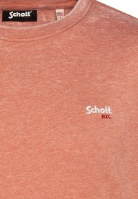 T-shirt a maniche corte di colore corallo-arancio realizzato in tessuto morbido, con scollatura a girocollo e logo ricamato in bianco "Schott NYC".