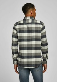 Heren flanellen overhemd in grijs, zwart en witte ruit. Voorzien van een button-down kraag, lange mouwen en een afgeronde zoom. Gemaakt van zacht, textuurstof.