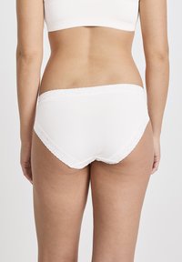 White cotton briefs with a lace trim on the waistband and leg openings, featuring a smooth texture and a low-rise cut at the back.