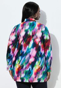 Farverig plisseret bluse med et livligt abstrakt mønster i røde, blå, grønne og lilla nuancer. Lange ærmer med knapmanchetter.