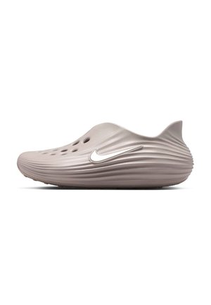 Ανοιχτό καφέ παπούτσι τύπου slip-on με υφή στην επιφάνεια, πλευρικές οπές αερισμού και λευκό λογότυπο Nike swoosh στο πλάι.