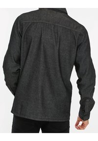 Ciemnoszara koszula wykonana z teksturowanej tkaniny, z długimi rękawami, zapinanym mankietem oraz wzorem z karczkiem na plecach.