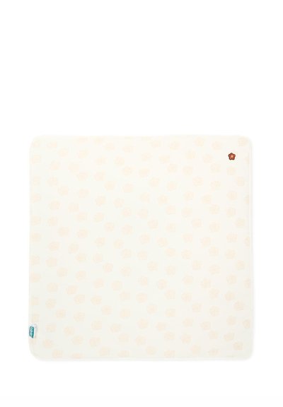 Kwadratowa kremowa tkanina z delikatnymi jasnopomarańczowymi kropkami i małym czerwonym kwiatowym emblematem w jednym rogu.