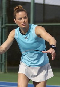 Lichtblauwe mouwloze sporttop met gaasaccenten en een ronde zoom, gecombineerd met een witte geplooide rok, op een tennisbaan.