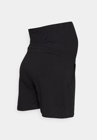 Calções pretos feitos de um tecido macio e elástico, com uma cinta larga e bolsos laterais. O design é simples e funcional.