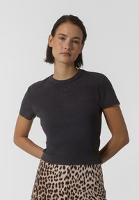 Mörkgrå, kortärmad ribbad t-shirt med rund hals och subtil logodetalj på bröstet, i kombination med en kjol i leopardmönster.