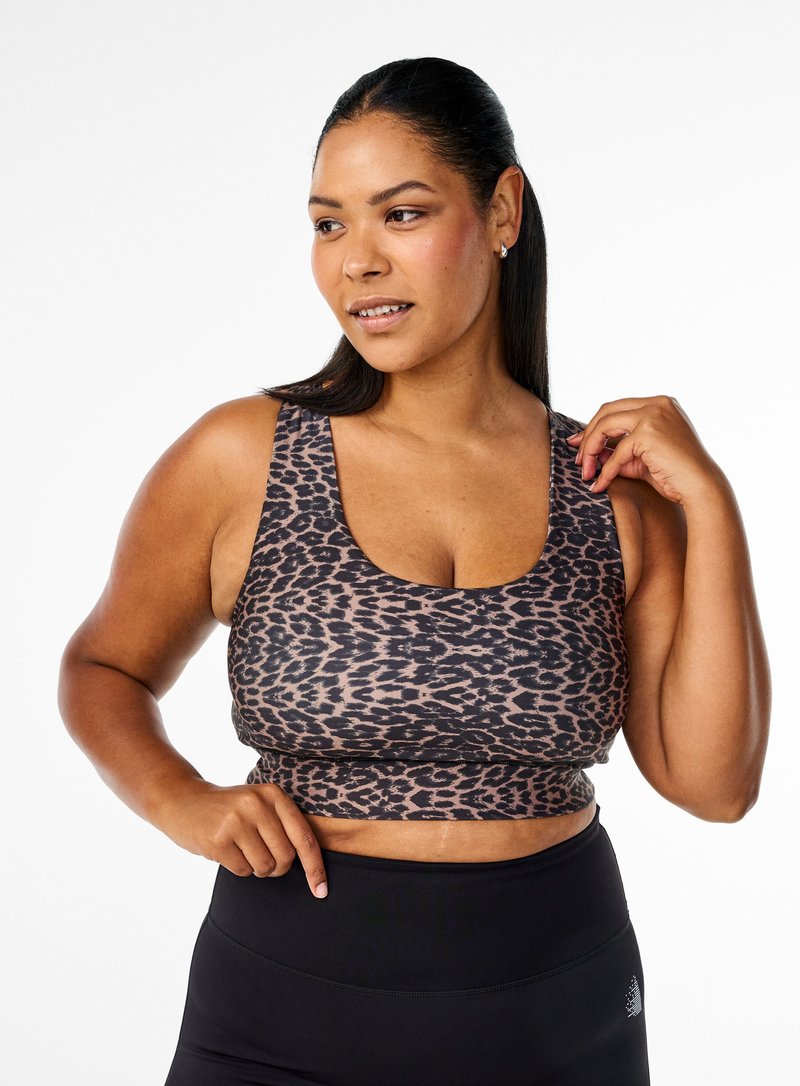 Sport-BH im Leopardenmuster aus weichem Material mit Rundhalsausschnitt und breiten Trägern, kombiniert mit hochtaillierten schwarzen Leggings.