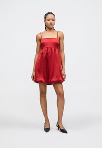 Rotes Satinkleid mit einem taillierten Oberteil, Spaghetti-Trägern und einem lockeren Rockteil. Glatte Textur, knielang und am Saum sanft gerafft.